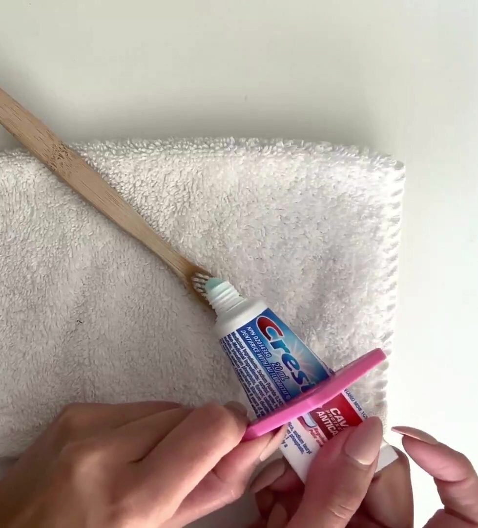 A pink 3D printed toothpaste squeezer being used on a tube of toothpaste