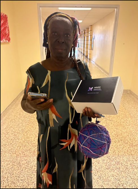 A community member holding an MNDX device box in a hallway