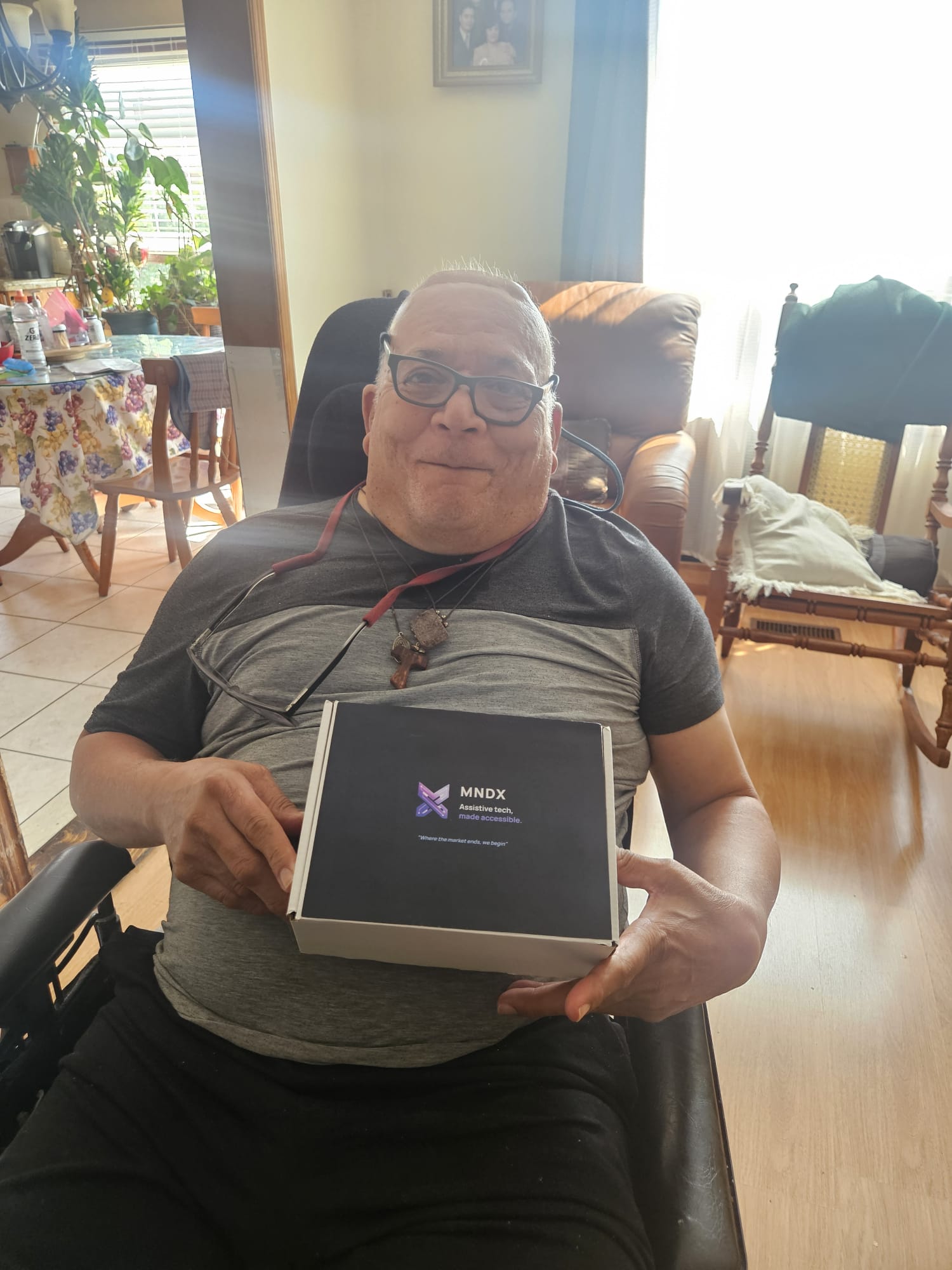 A man seated in his chair at home holding an MNDX device box