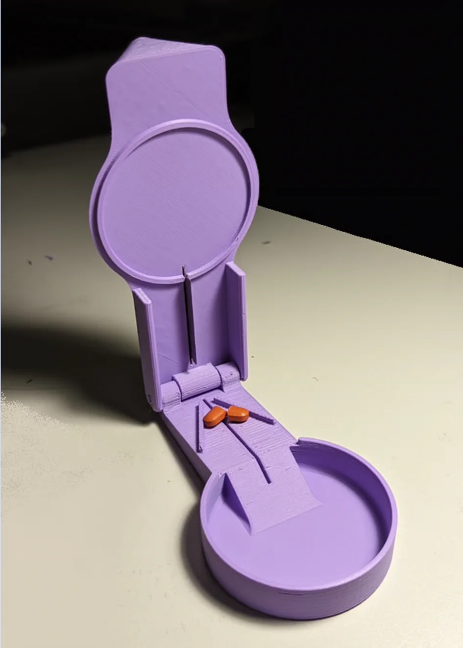 A 3D printed pill splitter with a pill centered in the slot