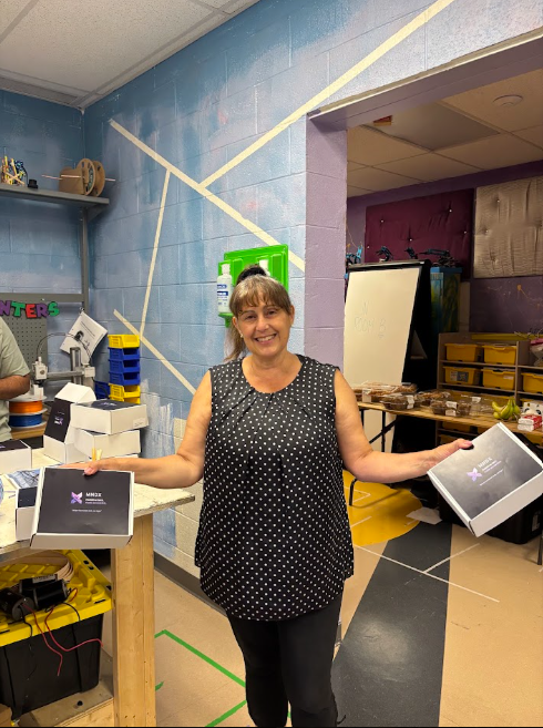 A community member holding two MNDX packages at the makerspace